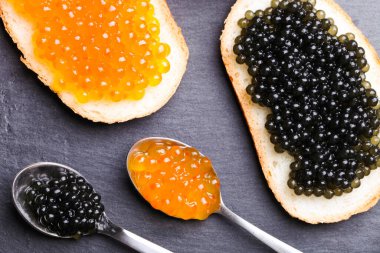 Siyah mersin balıklı sandviçler ve servis tahtasında kırmızı somon balığı havyarı..