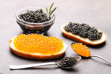 Siyah mersin balıklı sandviçler ve servis tahtasında kırmızı somon balığı havyarı..