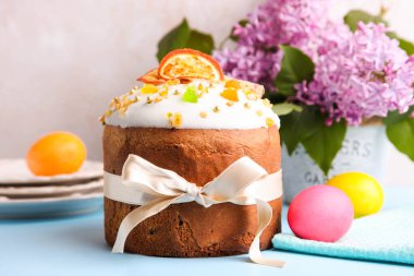 Renkli yumurtalı Paskalya pastası ve mavi ahşap arka planda bir dal leylak..