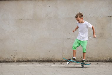 Çocuk kaykayı duvarın arka planında sürüyor. Aktif spor.