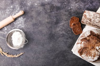 Ev yapımı çavdar ekmeği, üzerine un serpiştirilmiş mutfak gereçleri serpiştirilmiş..