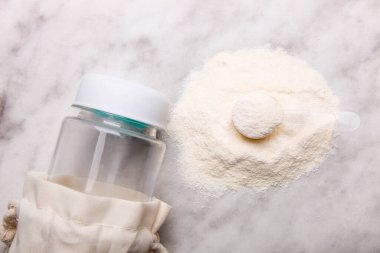 Beyaz protein tozu yığını. Ölçme kaşığı ve mermer arka planda şişe var..