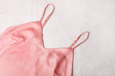 Beyaz arka planda pembe saten kadın geceliği..