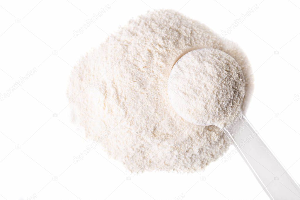 Heap of white protein powder with measuring spoon isolated on white background.