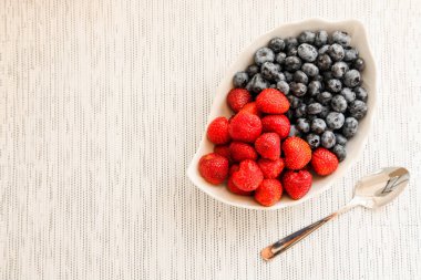 Tarafsız bir arkaplanda bir kasede yaban mersini ve çilek. 