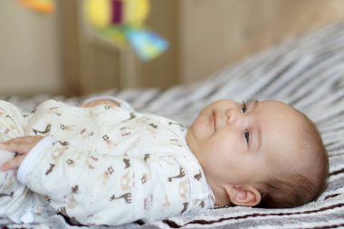 Renkli oyun minderi ve spor salonunda çıngıraklı oyuncaklarla oynayan sevimli bir erkek bebek. Çocuk aktivitesi ve çocuk gelişimi için oyun merkezi. Beyaz güneşli kreşte yeni doğmuş bir çocuk oyuncağı tekmeliyor ve kapıyor. Yüksek kalite fotoğraf