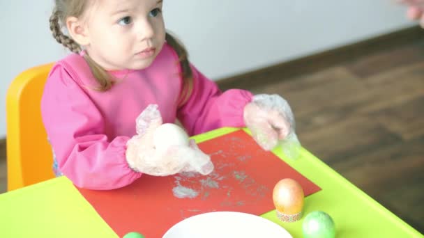 复活节 逾越节 创造力 游戏概念 3岁的斯洛文尼亚白人小女孩穿着粉色礼服 戴着塑料手套画复活节彩蛋的特写镜头 — 图库视频影像
