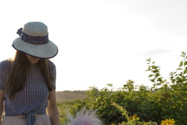 Kadınlık, kaynak stili, mutluluk, doğa, yaz, tatil - saman şapkalı mutlu genç kız Kafkas Slav görünüşü yaz günbatımında lavanta tarlasında gülümsüyor ve dinleniyor. Kopya alanı.