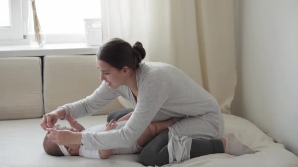소아과 어머니는 개월된 키스하고 부드러운 침대에 햇살을 행복하게 여긴다 — 비디오