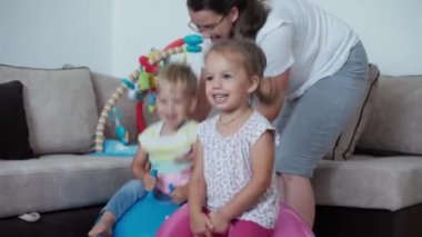 Çocukluk, annelik, oyunlar, yetiştirilme, gelişim konsepti. Genç anne, anaokulu kızı ve oğluyla birlikte spor yaparken eğleniyor, çocuk oyun odasında gülümsüyor. İki çocuk kreşte..