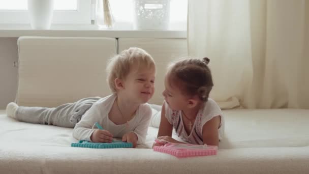 자녀가 침대에 연필을 글씨를 그리는 여동생들은 즐겁게 키스하고 웃으며 아이들은 — 비디오