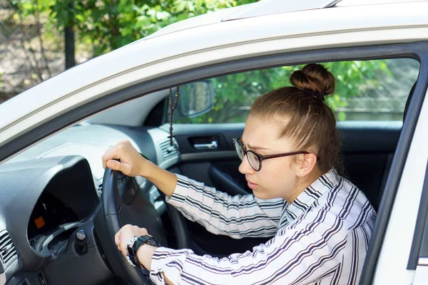 young rich successful business lady in glasses and business clothes sitting in car looking at watch on hand hurries late for work, important conference or meeting. Negative emotions of fear anxiety.