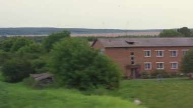 Ulaşım, seyahat, karayolu, demiryolu, manzara, yakınlaşma konsepti - sarı buğday tarlası manzarası, elektrik direklerinin ve ormanın penceresinden donuk bulutlu yaz akşamında hız treni manzarası