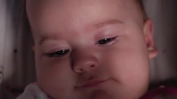 Νήπιο, παιδική ηλικία, συναίσθημα έννοια - Ακραία γκρο πλαν πορτρέτο του καφέ-eyed παχουλό νεογέννητο ξύπνιο χωρίς δόντια μωρό 7 μηνών συλλαμβάνεται ματιά στην κάμερα που βρίσκεται σε λευκό κοστούμι του σώματος με teether σε καροτσάκι — Αρχείο Βίντεο