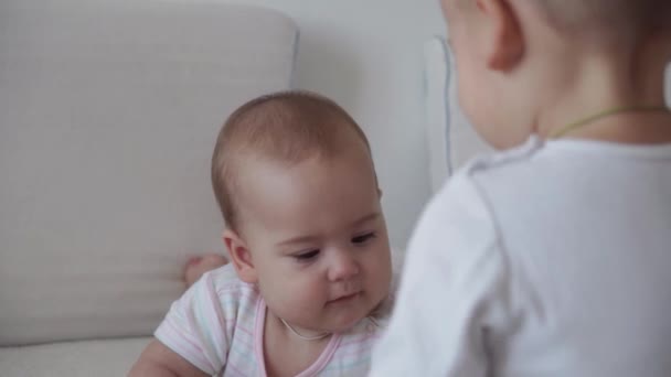 Familie, Kindheit, Säuglingskonzepte - Zwei neugeborene Babys und Jungen spielen mit Spielzeug auf dem Bett. Geschwister kleiner Junge und Mädchen Bruder und Schwester haben Spaß und lachen, glückliche Kinder zu Hause in Quarantäne. — Stockvideo