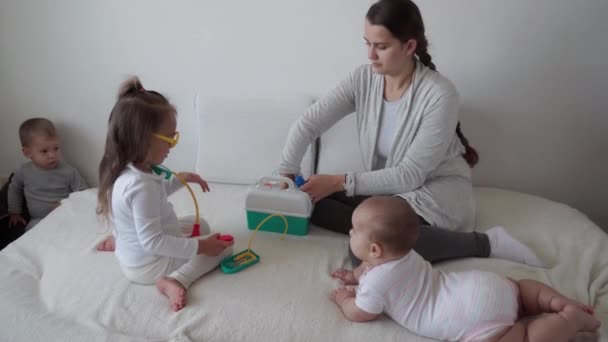 Medicína, rodina, herní koncepty - Soustředěné hravé děti nosí lékařské brýle stetoskop. Předstírej, že jsi doktorka, sestřičko, poslyš, usměj se maminko. — Stock video