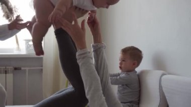 Çocukluk, oyunlar, büyük aile, izolasyon konsepti mutlu, sağlıklı, genç bir anne, küçük, sağlıklı bir kızı kaldırıyor, kanepeye oturuyor, komik kız anne kollarında uçuyor, birlikte eğleniyor.