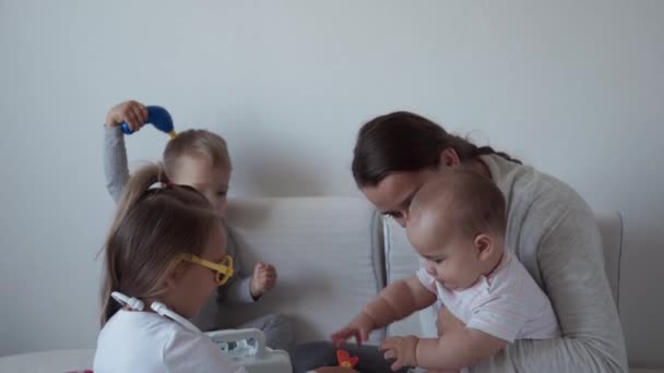 Geneeskunde, familie, spelconcepten - Geconcentreerde speelse kleine kinderen dragen een medische bril met stethoscoop. Doe alsof je dokter, verpleegster, luister glimlach mammie pasgeboren zusje adem diep, zitten op bed — Stockvideo