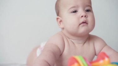 Bebeklik, çocukluk, ebeveynlik, gelişim, tıp ve sağlık konsepti - yakın plan çıplak yeni doğmuş çocuk, pembe bedenli neşeli uyanıklık, göbeğinde çok renkli oyuncaklarla gülümsüyor.