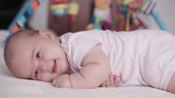 幼児期 小児期 医学と健康の概念 ぽっちゃり新生児の喜びの目覚めは横にある 笑顔をロールオーバーし おなかの上に横たわる悲しみを作ることを学ぶ — ストック動画
