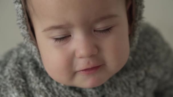 Smutek, niemowlę, koncepcja dzieciństwa - zbliżenie smutne, zdenerwowane, zmartwione, senne, przestraszone ośmiomiesięczne niemowlę pulchne dziecko w ciepłym swetrze z kapturem popatrz na kamerę płacze w histeryce w domu — Wideo stockowe