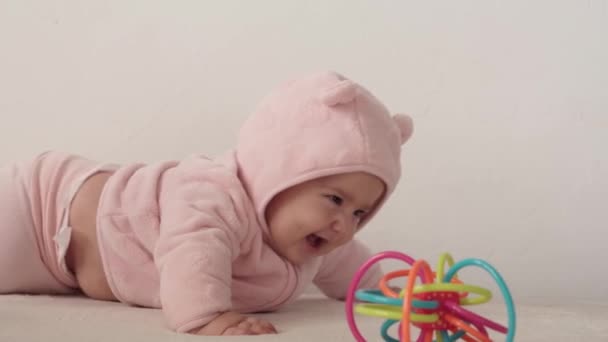 幼児、子供時代のコンセプト-新生児の目を覚ますの幸せなふっくら面白い茶色の目のぽっちゃりした顔のクローズアップ。歯のない7ヶ月赤ちゃんのグライムス目を閉じてベッドの上に寝そべって — ストック動画