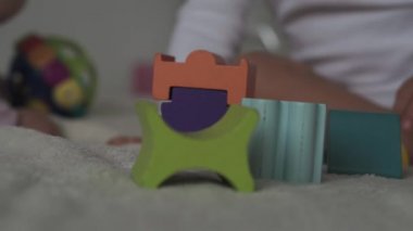 Çocukluk, aile, izolasyon, inşaat konsepti - 2 küçük mutlu çocuk yatağa oturmuş ahşap piramit inşa ediyor. 6-9 aylık yeni doğmuş kız çocuğu ve 2-3 yaşındaki oğlan evde motor becerileri için oyun oynuyorlar..