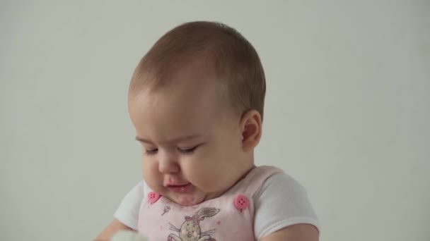 Criança, infância, higiene, conceito de cuidado - close-up de sorrir engraçado rosto gordinho de olhos castanhos de criança pequena acordada rói escova de cabelo. Happy Child se penteia com escova de cabelo no fundo branco em casa. — Vídeo de Stock