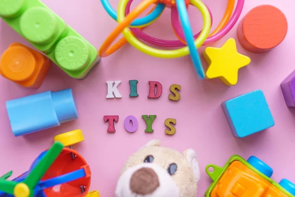Çocukluk, bebekler farklı türlerden çocuklar için renkli oyuncaklar. yumuşak oyuncak ayı, helikopter, kürdan, inşaatçı, biblolar, pembe arka plandaki araba. — Stok fotoğraf
