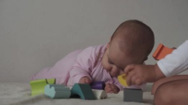 Çocukluk, aile, izolasyon, inşaat konsepti - 2 küçük mutlu çocuk yatağa oturmuş ahşap piramit inşa ediyor. 6-9 aylık yeni doğmuş kız çocuğu ve 2-3 yaşındaki oğlan evde motor becerileri için oyun oynuyorlar..