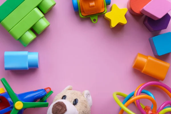 Infancia, bebés: juguetes de colores para niños de diferentes especies. oso de peluche suave, helicóptero, palillo de dientes, constructor, figuritas, coche sobre fondo rosa pastel. — Foto de Stock
