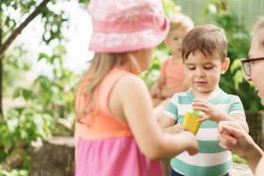 Hafifçe odaklan. Tatil, çocukluk, annelik, yemek kavramı. Annem kardeşlerinin dondurmasına bakıyor. 2-3 yaşlarındaki çocuklar bahçede buzlu şeker yiyorlar. Mutlu çocuklar piknikte tatlıdır.