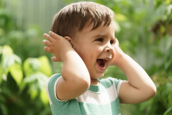 Lato, wakacje, dzieciństwo, koncepcje komunikacji. szczęśliwy mały zaskoczony chłopiec Perski wygląd wschodniej narodowości jest na zewnątrz. Dziecko pokazuje gest głuchego mężczyzny zakrywającego uszy rękami. — Zdjęcie stockowe