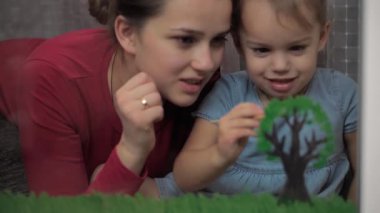 Çocukluk, annelik, yaratıcılık, doğa, sanat, bahar, yaz konsepti - 3-4 yaşlarında küçük kızı olan genç bir annenin pencere camına çizimi. kadın ve anaokulu kızı ağaç boyuyorlar..