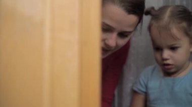 Çocukluk, annelik, yaratıcılık, doğa, sanat, bahar, yaz konsepti - 3-4 yaşlarında küçük kızı olan genç bir annenin pencere camına çizimi. Kadınlar ve anaokulu kızları çiçek boyarlar.