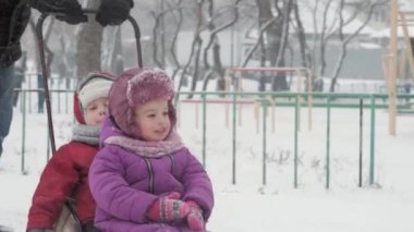 Kış, çocukluk, babalık, oyunlar, aile kavramları - kapanış iki mutlu anaokulu çocuğu kardeş kızakla kayarak eğleniyorlar babayla birlikte buz gibi havada parkta oynuyorlar.