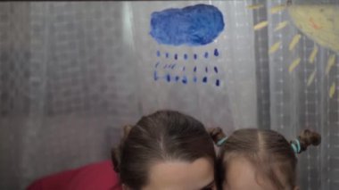 Çocukluk, annelik, yaratıcılık, doğa, sanat, bahar, yaz konsepti - 3-4 yaşlarında küçük kızı olan genç bir annenin pencere camına çizimi. kadın ve anaokulu kızı ağaç boyuyorlar..