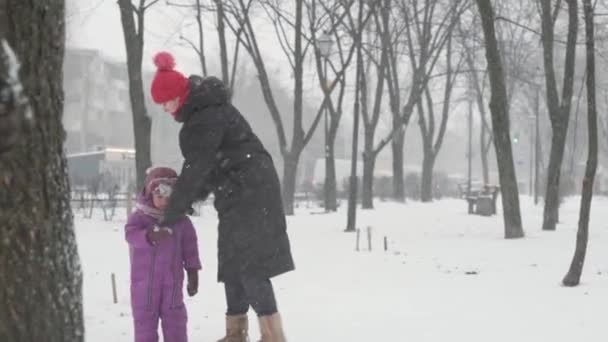Hiver, vacances, jeux, concepts de la famille heureux préscolaire tout-petit fille fille fuir jouer faire boule de neige anges de neige avec maman automne, se coucher dans la neige froid saison temps dans le parc en plein air — Video