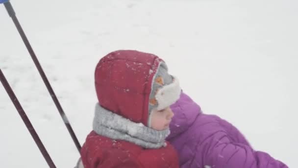 Invierno, Infancia, paternidad, juegos, conceptos familiares - de cerca Dos niños preescolares felices niños hermanos niños paseando en trineo divertirse jugar juntos con papá en las nevadas clima frío en el parque al aire libre — Vídeos de Stock