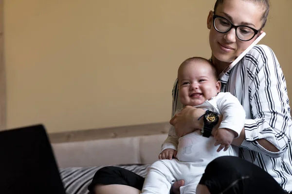 Infância, maternidade, conceitos de família - mulher de negócios rica sorridente bem sucedida Lady mãe sentar-se na cama com bebê infantil falando no telefone trabalhando no computador lap top em casa à distância dentro de casa — Fotografia de Stock