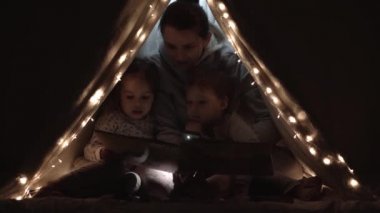 Otantik sevimli anne ve anaokulu çocukları evdeki çadırda kız ve erkek. Genç bir kadın 2-4 yaşlarındaki çocuklara kitap okurdu. Aile, Çocukluk, Annelik, Rahatlık ve Güvenlik kavramı