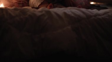 Çadırda tombul bir bebekle birlikte otantik sevimli bir anne. Genç bir kadın, 6-12 aylık bir çocukla akıllı telefon kullanıyor. Geceleri çadırda oturuyor. Aile, Çocukluk, Annelik, Rahatlık ve Güvenlik kavramı.