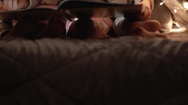 Otantik sevimli anne ve anaokulu çocukları evdeki çadırda kız ve erkek. Genç bir kadın 2-4 yaşlarındaki çocuklara kitap okurdu. Aile, Çocukluk, Annelik, Rahatlık ve Güvenlik kavramı