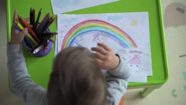 Gyermekkor, művészet, oktatás, kreativitás, anyaság koncepció - autentikus fiatal anya két gyerekkel óvodai kreatív tehetséges gyerek fiú 2-4 éves és csecsemő baba rajzok festékek ceruzával kép ül az asztalnál — Stock videók