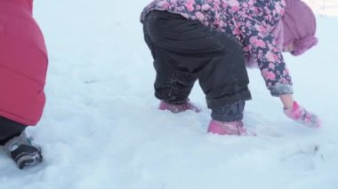 Kış, tatil, oyunlar, aile konsepti ağır çekimde iki mutlu anaokulu çocuğu, şapka ve eldiven takmış iki çocuk ve annemle el ele kar kusuyorlar. Soğuk mevsimde parkta açık havada