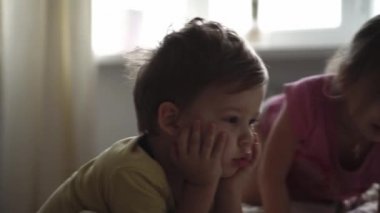 Aile, rahatlık, çocukluk, arkadaşlık kavramları - otantik üç anaokulu çocuğu küçük çocuklar, kardeşler akıllı telefon cihazıyla çizgi film izliyorlar.