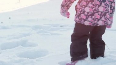 Kış, tatil, oyunlar, aile konsepti - çocuk derin karda koşar. Çocuklar karlı yolda yürür. Anaokulu çocuğu kardeşler, soğuk mevsimde kar altında siyah tulum giymişler.