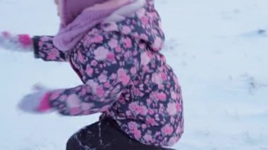 Kış, tatil, oyunlar, aile kavramları. Küçük, otantik anaokulu öğrencilerinin orta planı. Mor elbiseli kız, karla kaplı çayırda kırsalda karla oynuyor. çocuk karlı alanda koşar.