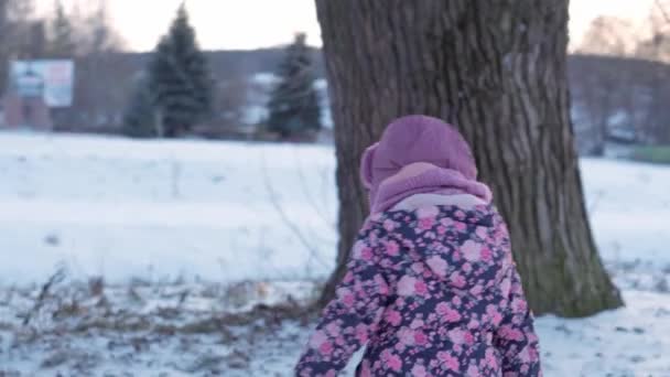 Inverno, férias, jogos, conceito de família - plano do meio de pequeno pré-escolar autêntico menor 3-4 anos de idade menina em roxo no prado coberto de neve brinca com neve antes do pôr do sol. criança corre na área nevada — Vídeo de Stock