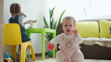 Çocukluk, aile kavramı, üç kardeş çocuk evde eğleniyor. Karantinada, oyun odasının zemininde küçük toplarla oynayan tatlı çocuklar. Bebek tek başına yürümeyi öğreniyor.